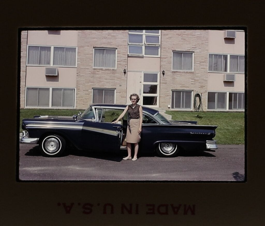 color slide of a white woman posing with a navy blue sedan
