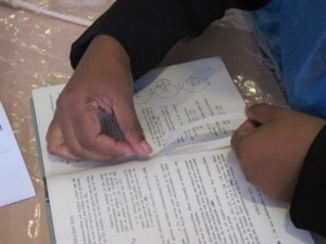Student is attaching a loose page in a book using document repair tape