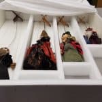 A large box container four marionettes in separate foam compartments.