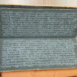 The original Burmese manscript is open and displaying white Pali script on black paper.