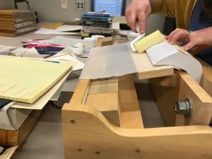 The pages of a book fanned to one side and glued using adhesive on a roller