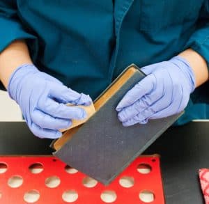 Student employee uses sponge to clean a dusty book.