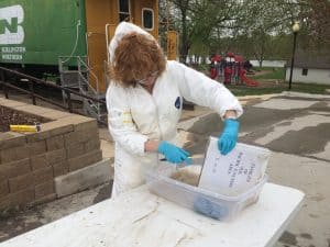 Cindy Opitz holds binder over a bucket of water and uses a brush to clean the pages.