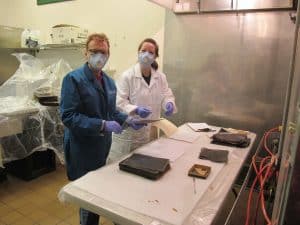 Kraft and museum employee wearing face masks, lab coats and gloves rehouse photographs