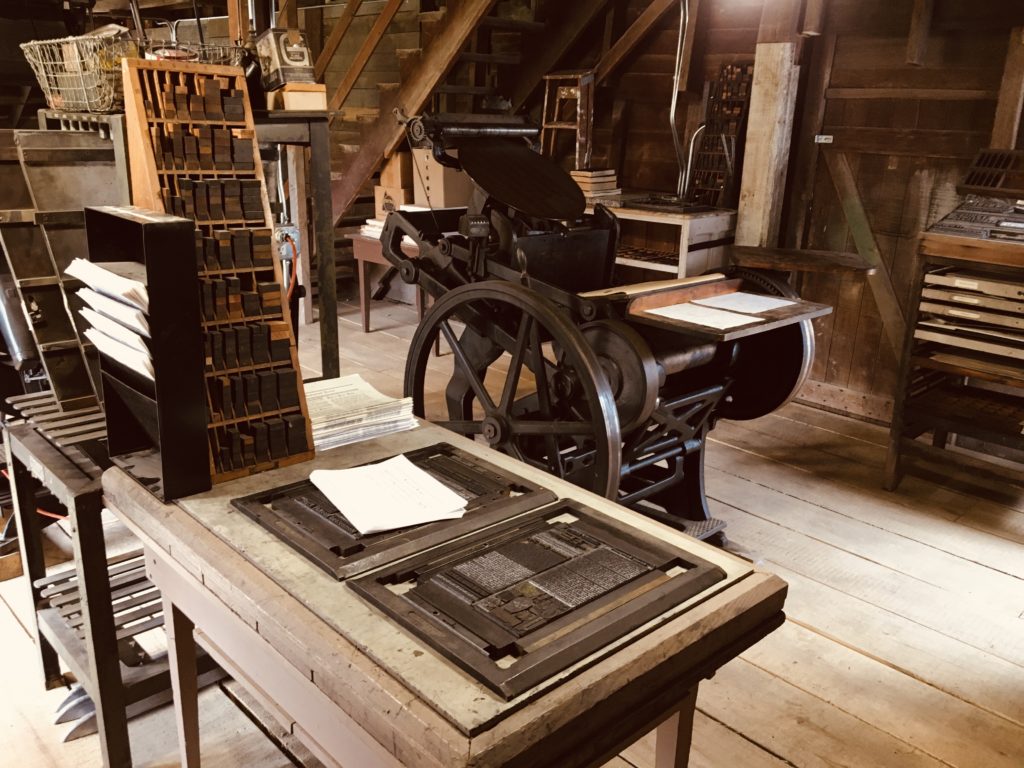 Historical platen press with set type and printing equipment. 