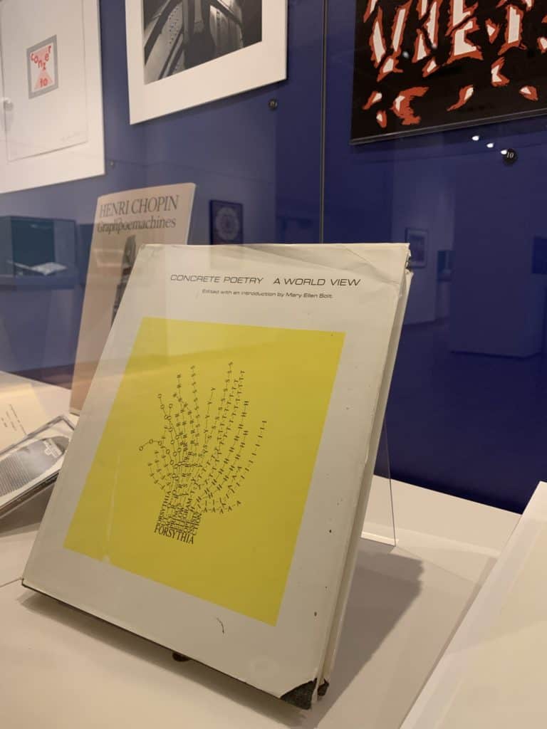 White book with yellow square on the front. The square is occupied by a lavender sort of plant created by typing various letters with a typewriter.