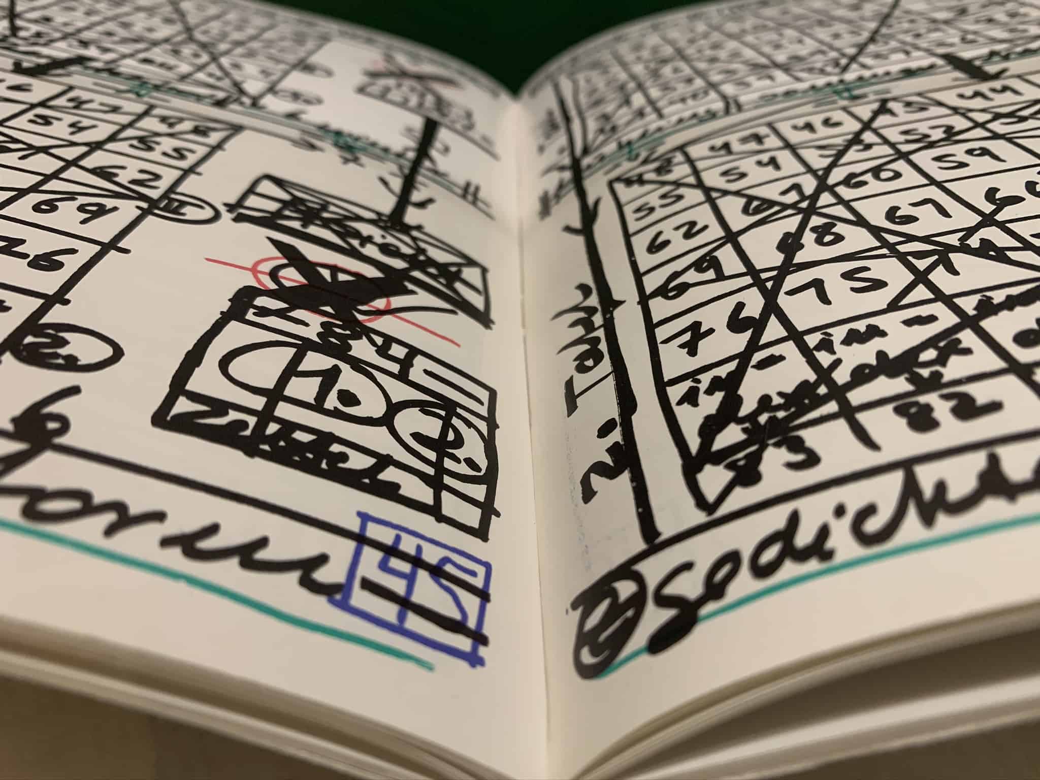 A book open to pages filled with hand drawn grids and numbers.