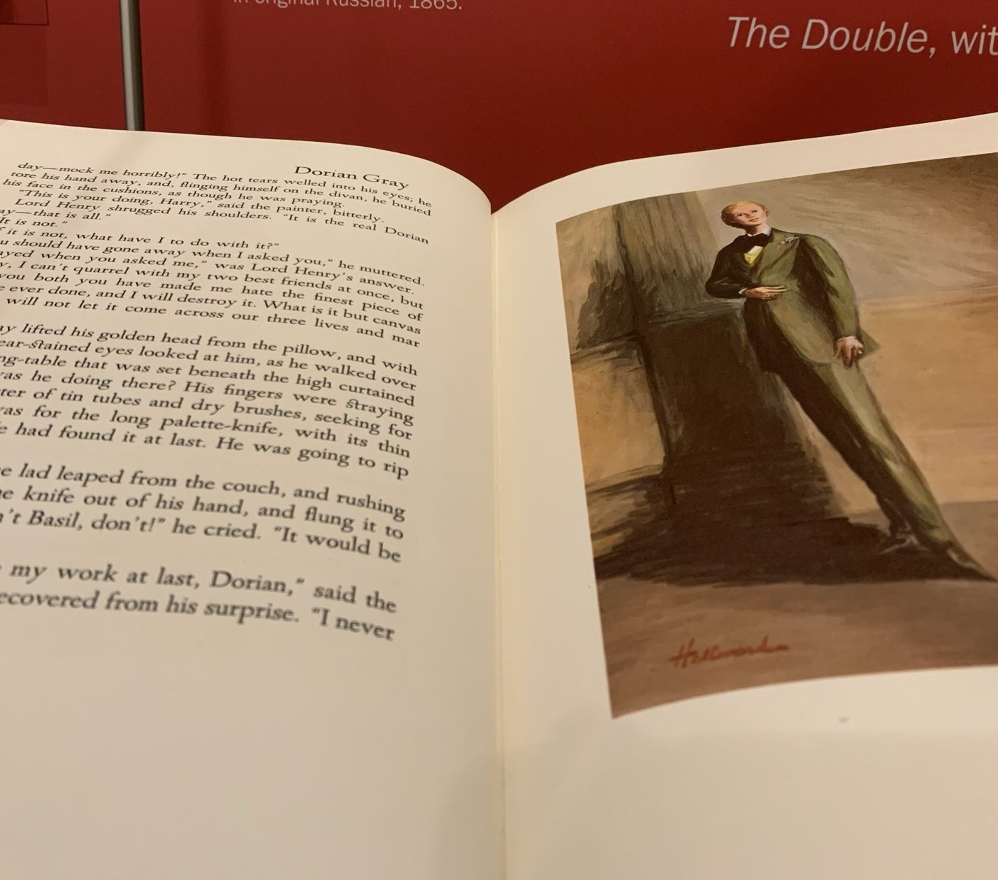 Oscar Wilde's novel The Picture of Dorian Gray is open to a portrait of Dorian Gray. He stands facing the reader. He wears a green suit and has a pleasant expression.