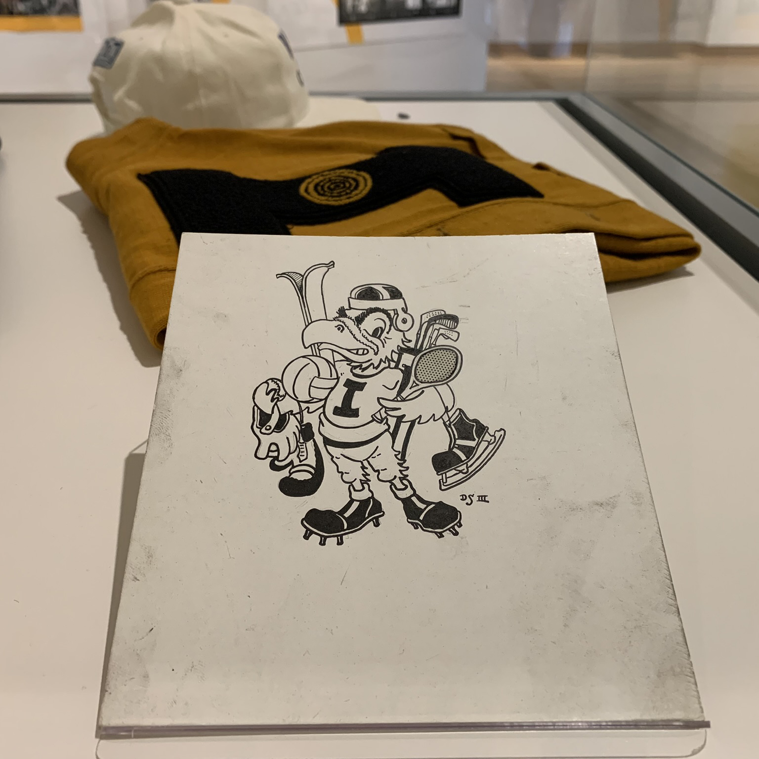 A sketch of Herky wearing football gear and holding sports equipment.