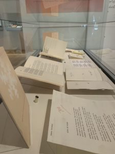 A display case filled with papers and books demonstrating the process from draft to completion of a small book by Tomaz Salamun called Snow.