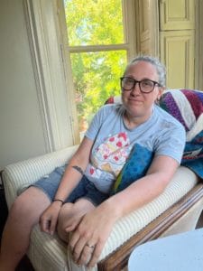 Curator Madde Hoberg sits in a chair looking at the camera.