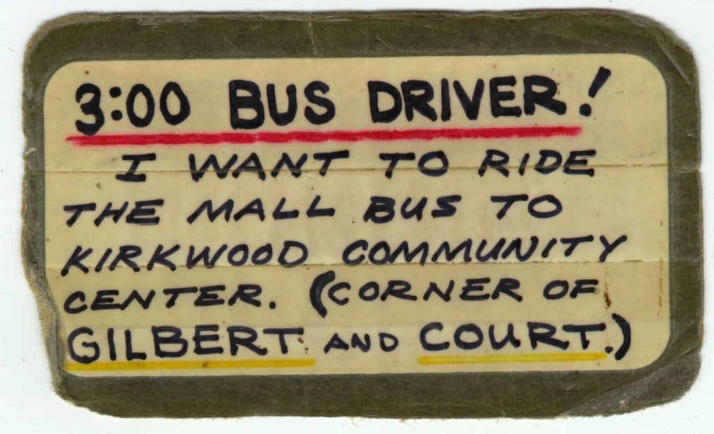 A small laminated note that says: 3 o'clock bus driver! I want to ride the mall bus to Kirkwood Community Center. Corner of Gilbert and Court.