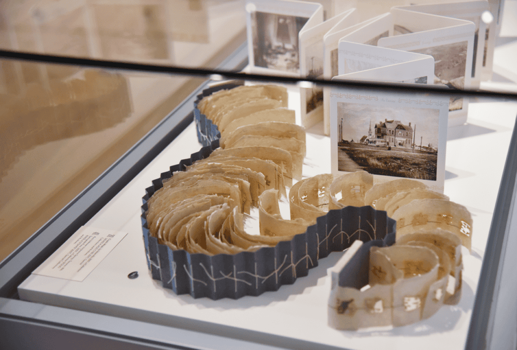 Two different pieces of book art snake and wind their way around one another. One is a series of sepia photographs from Tacoma, Washington and the other is a type of accordion book made with handmade paper and hand stitching.