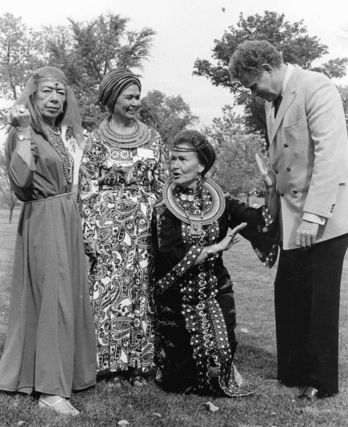 Three women in costume for an opera stand outside with conductor James Dixon.