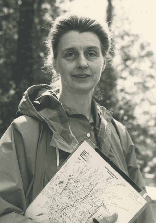 Shirley Briggs stands outdoors in a jacket holding a clipboard.