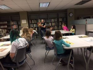 Curator Kären Mason shows the girls some artifacts from IWA collections.