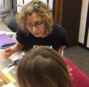 Assistant curator Janet Weaver helps a girl write her exhibit caption, "And the women powered through it!"