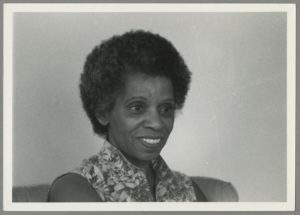 Black and white portrait of a smiling Black woman with an afro.