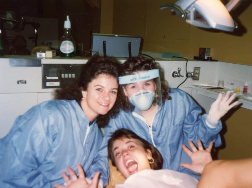 Three smiling female students wearing scrubs