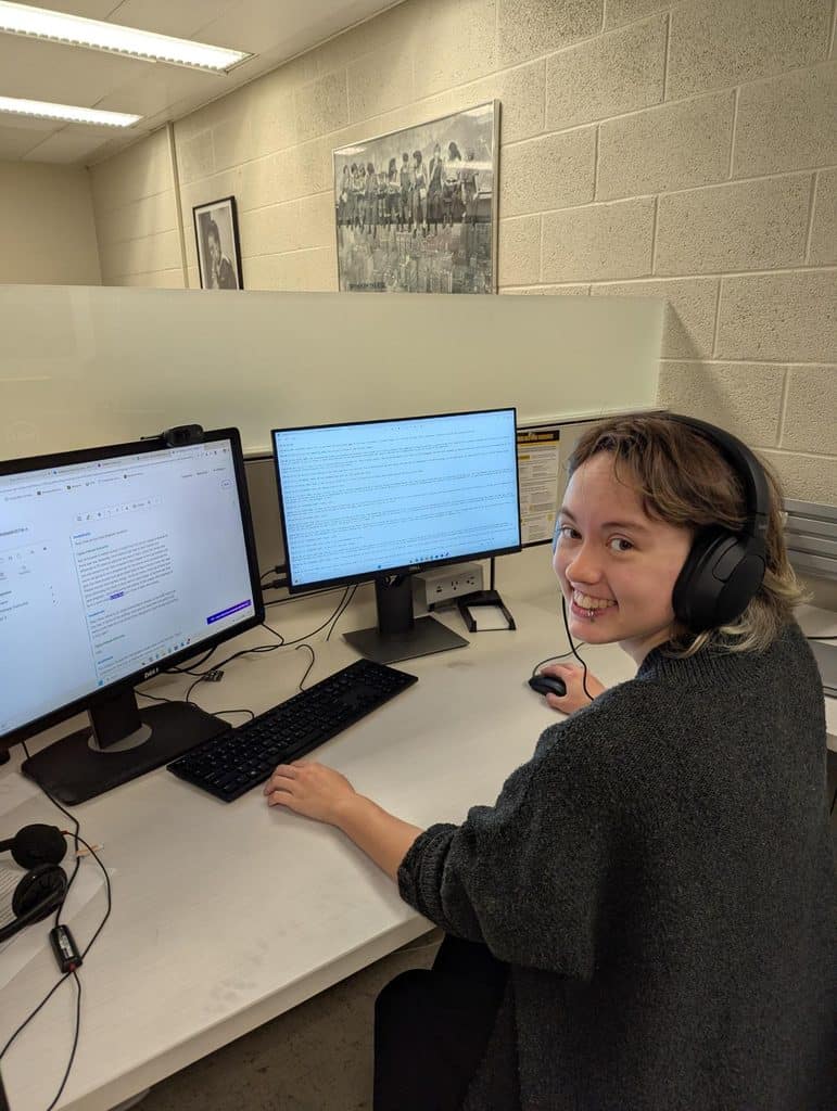 Student at dual monitor computer with transcription software on the screen
