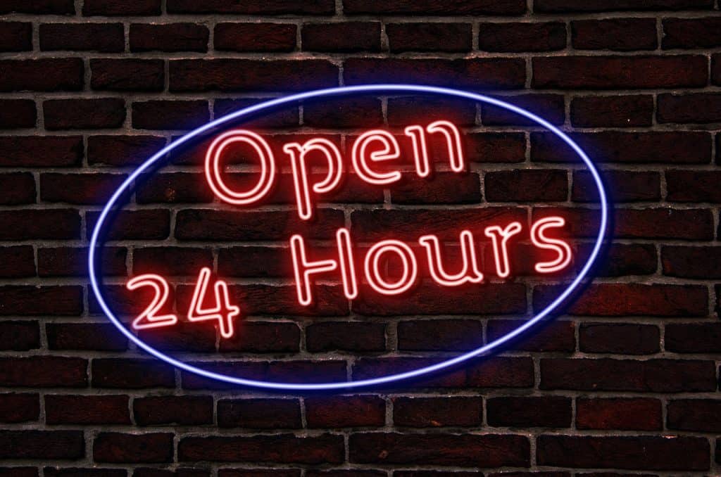 open 24 hours sign on brick wall