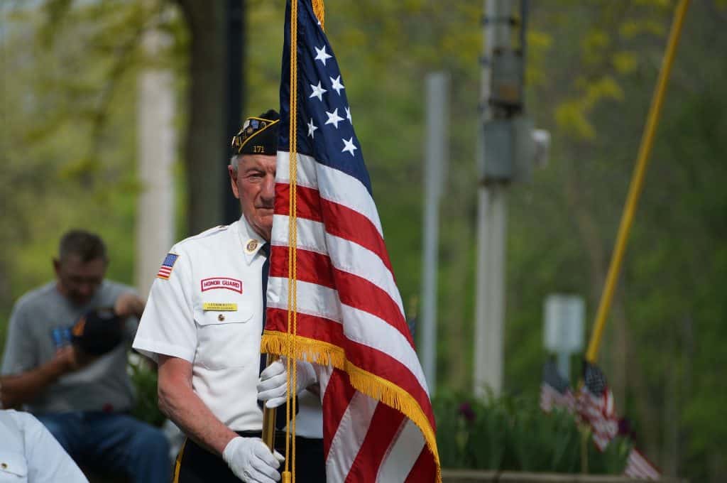 image of white man with flag, wearing honor guard uniform, carrying flag