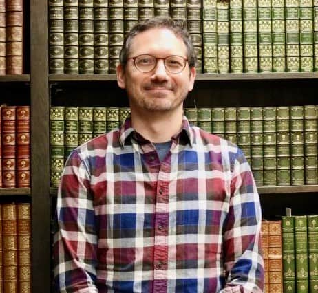 photo of Damien Ihrig, white man, in front of a bookcase