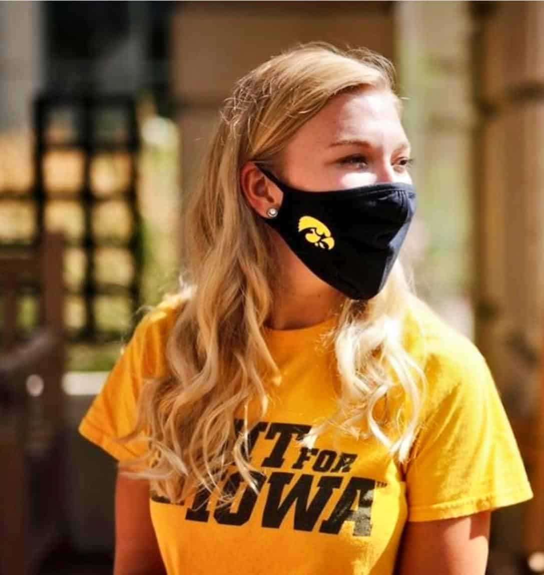 young woman, blonde hair, yellow shirt, black face mask with tigerhawk logo