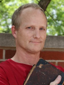 image of Duncan Stewart, white man, posing with rare book outside