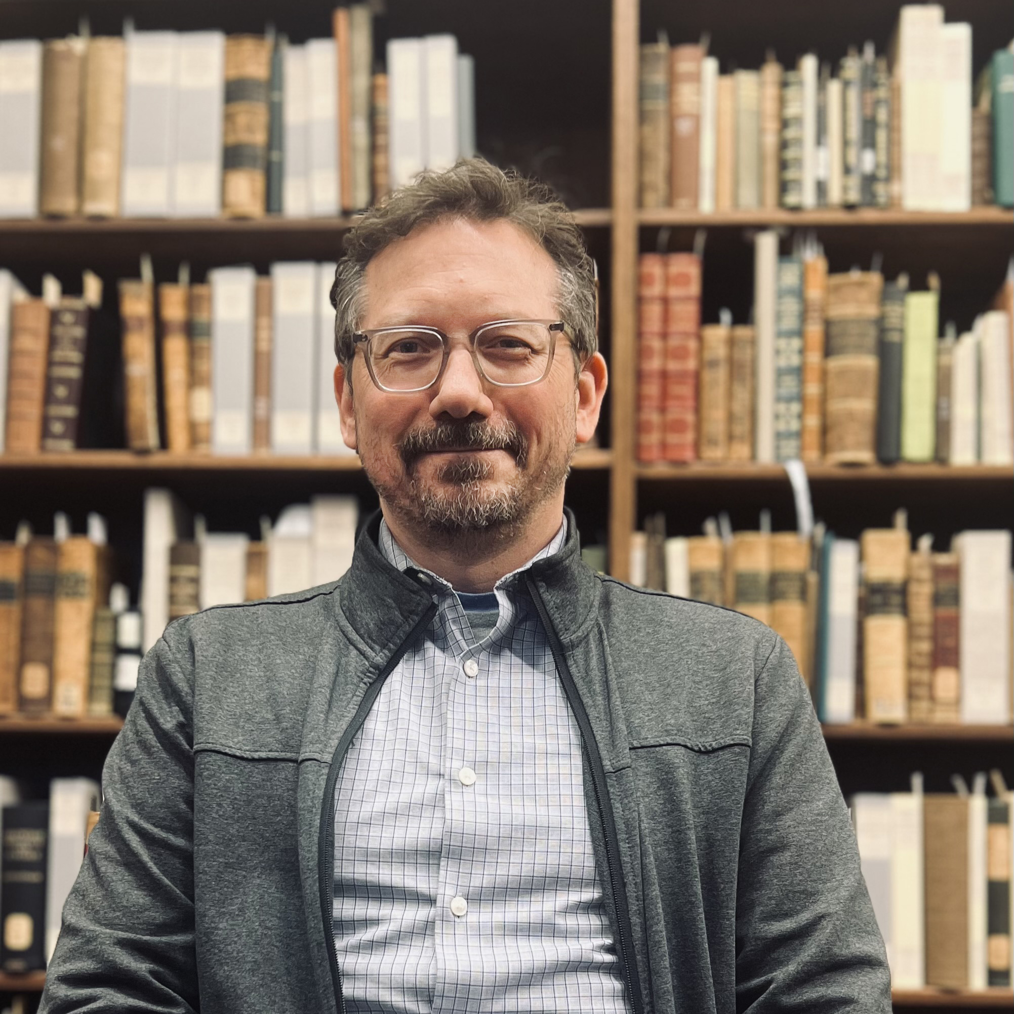 Damien Ihrig, white man in front of bookcases of rare books