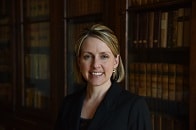 Heather Healy, white woman, blonde hair, in front of books