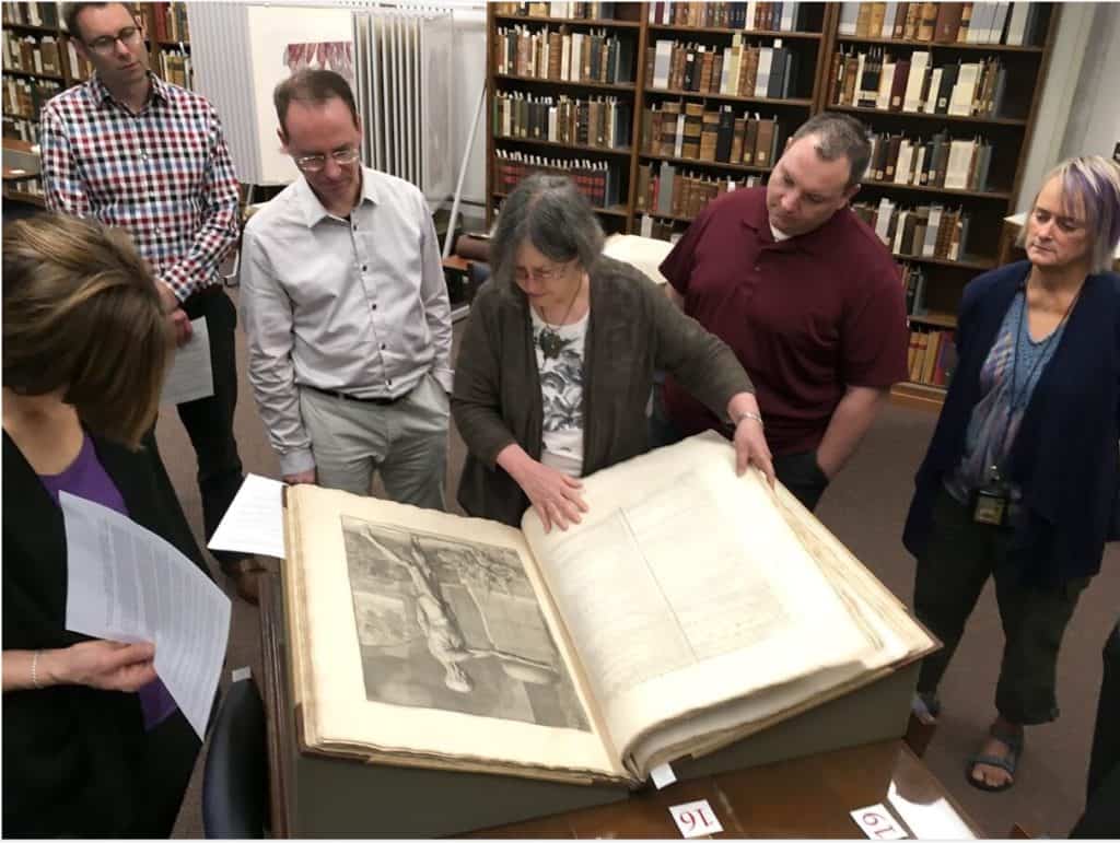 group of people look at oversized rare book