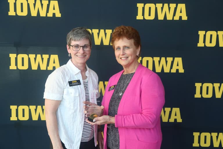 two staff members holding award