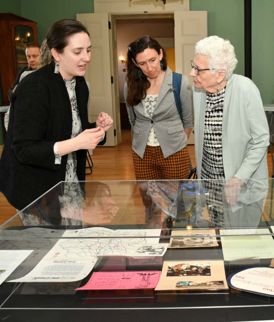 Kate Orazem shows Iowa women’s political history materials to Michael Eynon-Lynch and Jean Lloyd-Jones