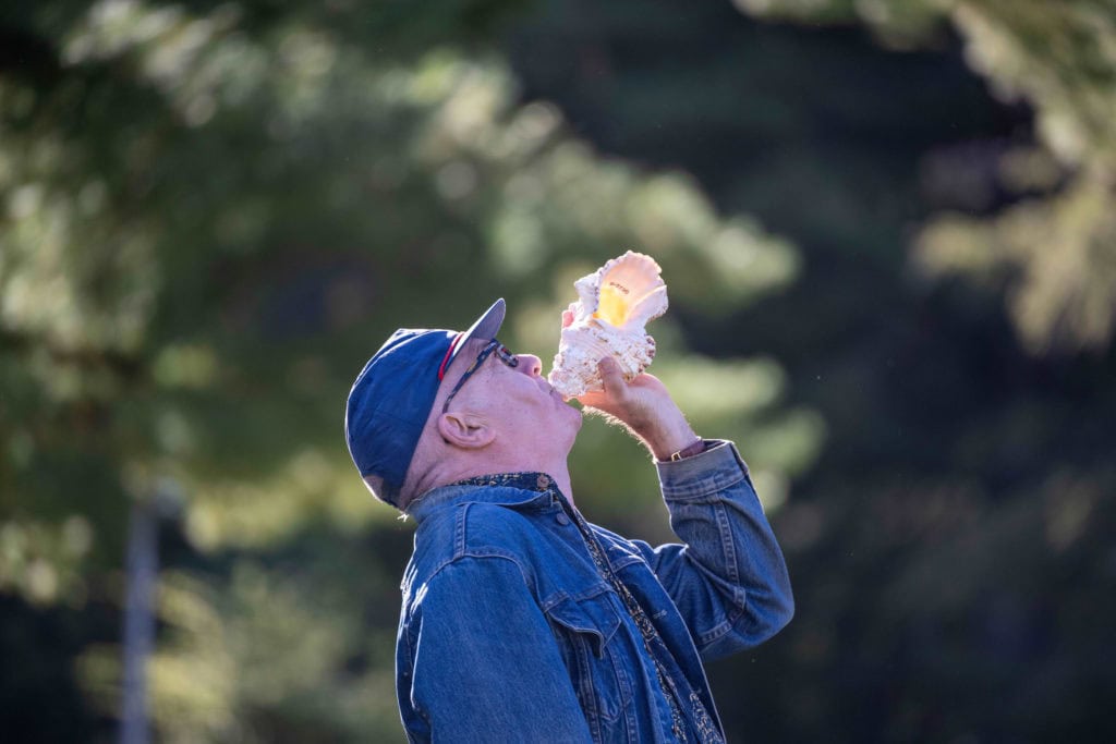 Steve Schick blows into a conch shell