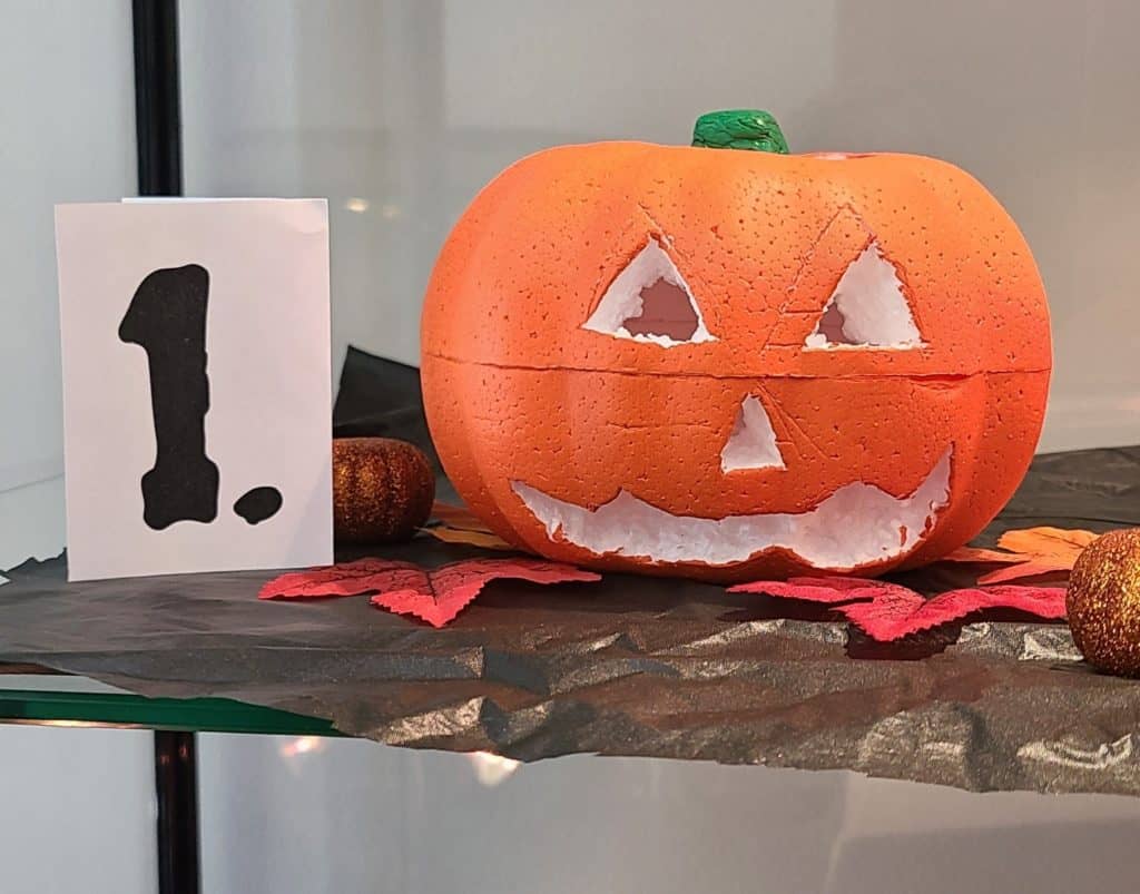 Pumpkin carved to have triangle-shaped eyes and nose with a smile with teeth