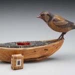 Image of the artiwork titled "sentinella" with a wooden boat filled with metal type, a wooden bird, and a small book with a coptic binding