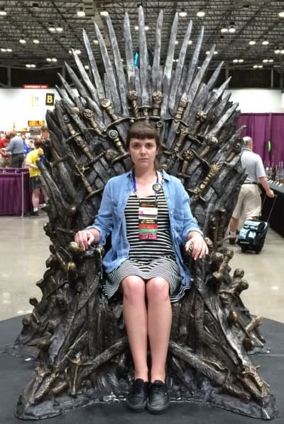 Laura Hampton sitting on the Iron Throne at World Con