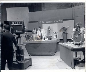 Fun with boxes: man on tv set with robots made of boxes