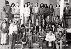 Black and white photo of large group of people sitting on steps and standing