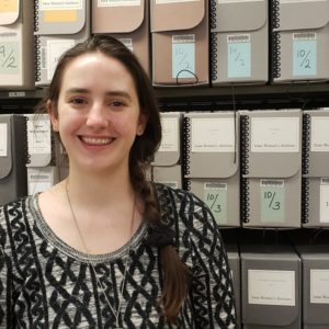 Woman standing in front of shelves of labeled archives boxes in Special Collections.