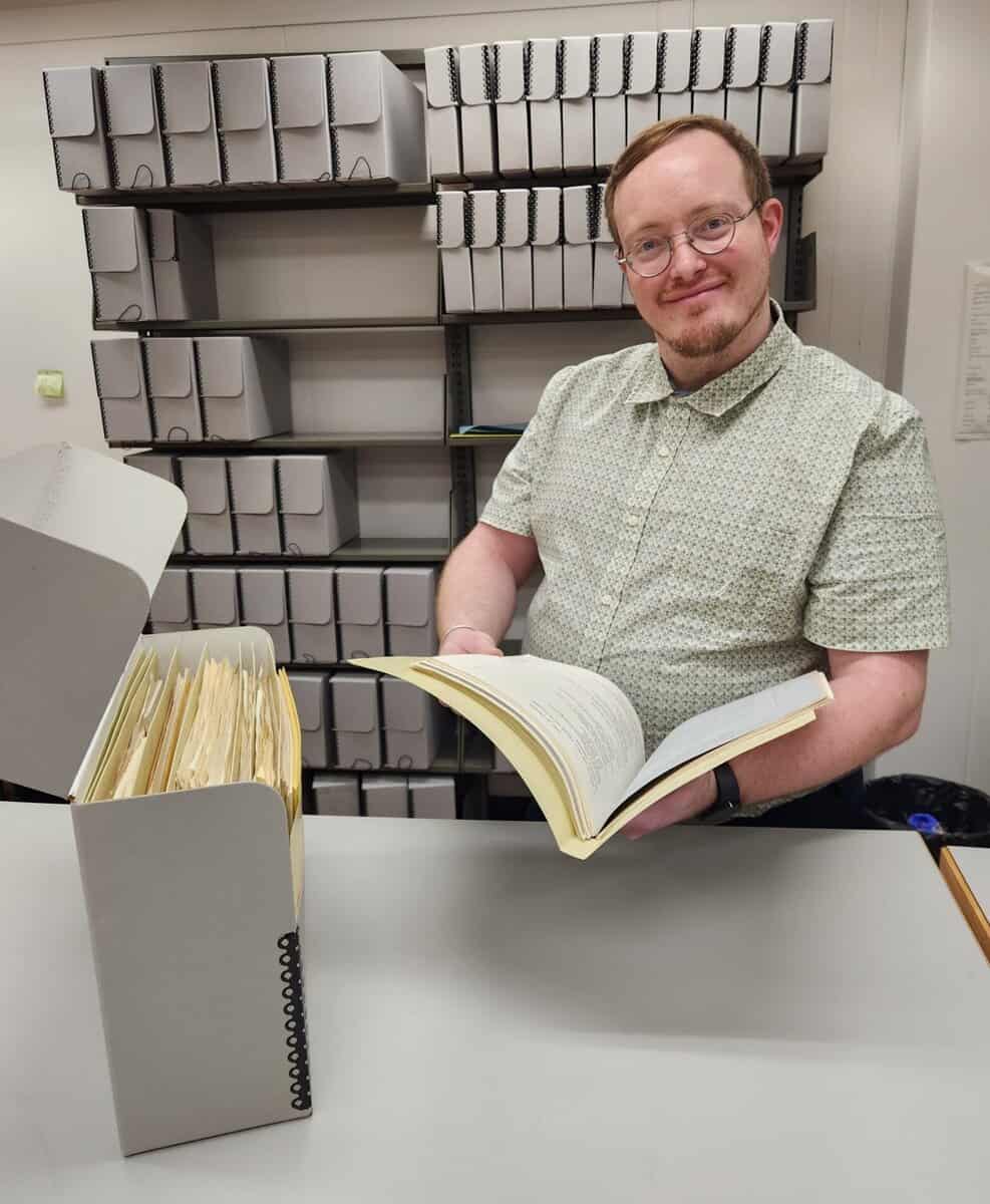 Man with archival box smiles at camera
