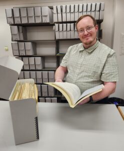 Man with archival box smiles at camera