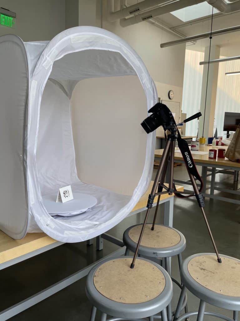 Video production studio setup with a camera, tripod, photo lightbox and turntable.